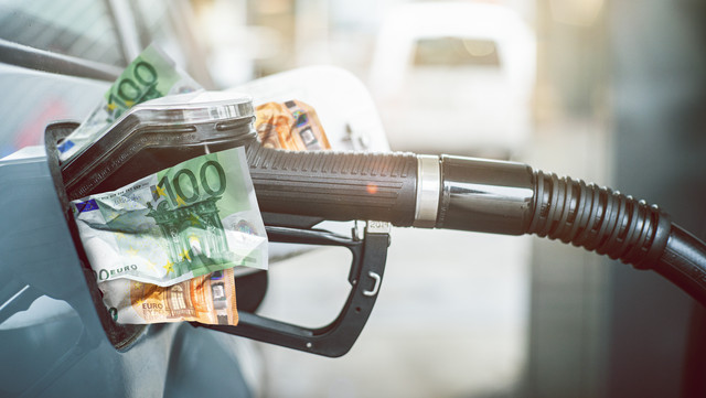 Eine Zapfpistole füllt Geldscheine in den Tank eines Autos 